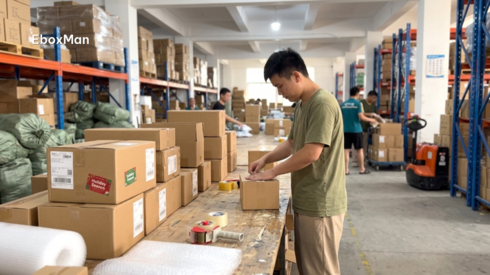 Warehouse worker packing parcels for Christmas shipping from China